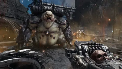  The Dark Ages' game play. A massive creature with frog-like trunk and turtle-esque head roars at the player character, exposing giant fangs. Two giant cannons take the place of its arms and it wears a metallic backpack - presumably feeding ammo to the weapons. The player holds a shield lined with saw blades on one side and an elaborate gun bedecked with a skull on the other.