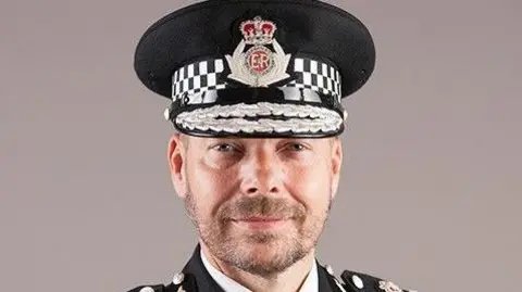 Headshot of Rod Hansen in full uniform, including a hat with the crest for Gloucestershire Police on it