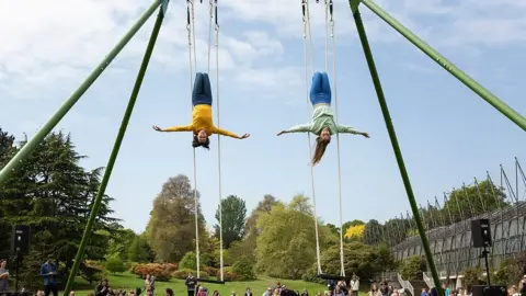 Suzanne Heffron performers on a giant swing