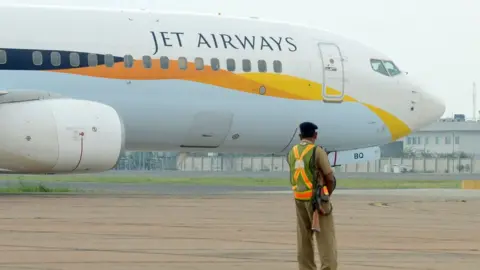 Getty Images An Indian security official looks on as an aircraft of Jet Airways taxies after landing at Indira Gandhi International Airport in New Delhi on September 12, 2012