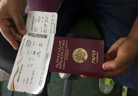 Reuters A passenger displays an Ethiopian passport and an Ethiopian Airlines boarding pass as he sits inside ET314 flight to Eritrea"s capital Asmara at the Bole International Airport in Addis Ababa, Ethiopia July 18, 2018.