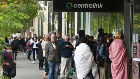 Getty Images Hundreds of people queue outside an Australian government welfare centre, Centrelink, Melbourne