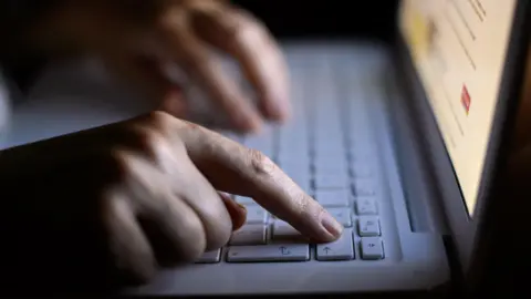 PA Media Person holding their fingers over a laptop keyboard.