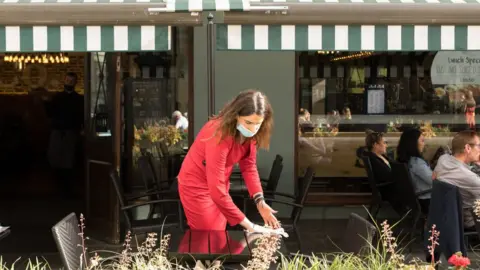 SOPA Images A waitress cleans a table outside a restaurant in Soho, London