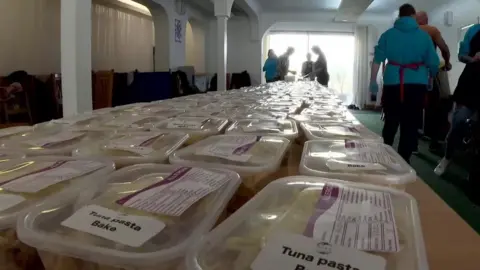 BBC A batch of boxes containing food, to be distributed to people in need