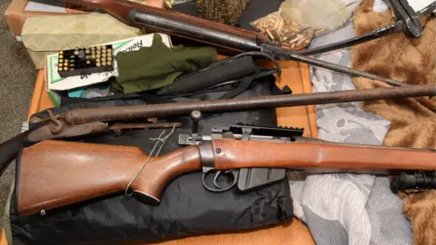 ERSOU Weapons are laid out on a table. They are old-fashioned wooden weapons, spread on some bedding.