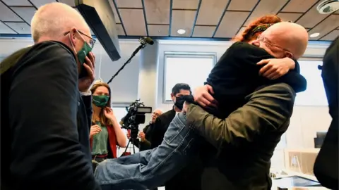 Reuters Environmental activists hug in court after a judge rules that Shell must cut its emissions