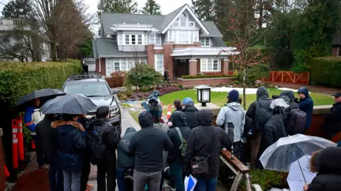 Getty Images Media stand outside the home of Meng Wanzhou as they wait for her to leave for a court appearance in Vancouver