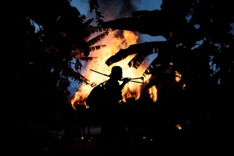 Ueslei Marcelino / REUTERS A man from the Guajajara community stands by a fire at a loggers camp