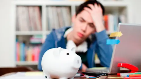 Getty Images Student in front of piggy bank