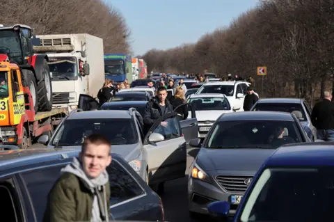Reuters People wait in a traffic jam as they leave the city of Kharkiv, Ukraine, 24 February 2022