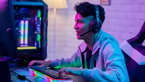 An Asian man playing a game on a desktop computer