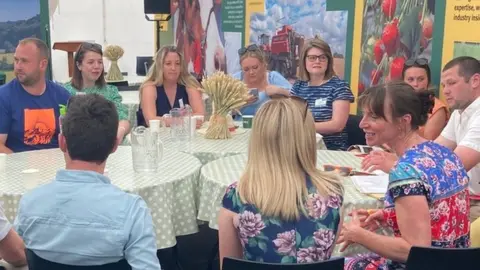 Younger farmers talking to each other around a table.