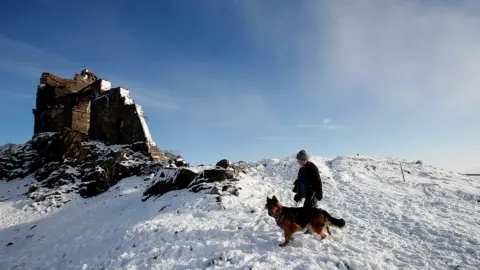 PA A woman walks her dog at Mow Cop Folly, Cheshire