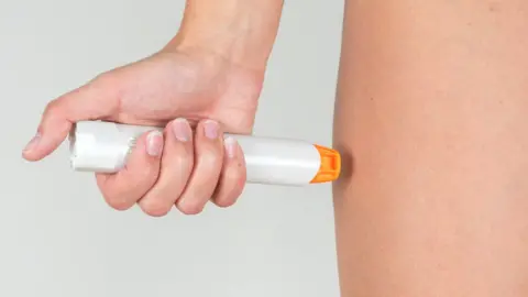 Getty Images Woman using an adrenaline auto-injector pen
