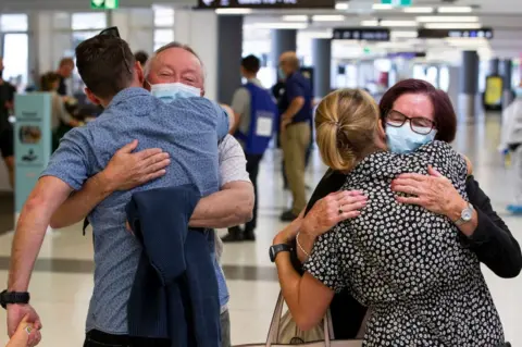 Getty Images Passengers are greeted by loved ones as a flight from Sydney arrives at Perth Airport on December 8, 2020 in Perth, Australia. Western Australia has eased its COVID-19 border restrictions.