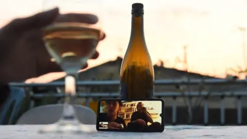 AFP A woman shares a drink with friends via a video call