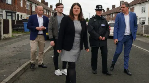 PA Media Emily Spurrell (centre) with local councillors, Steve Rotheram (right) and Serena Kennedy (second from right)