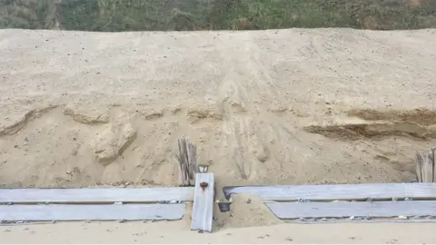 Christine Matthews/Geograph Sand is piled up behind wooden defences at Mundesley