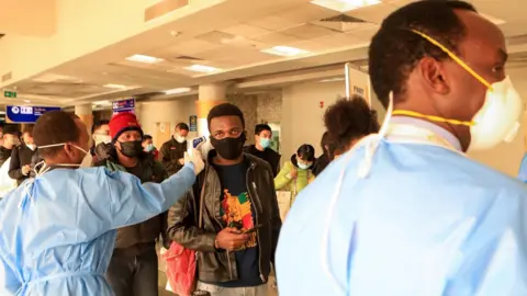 EPA Passengers wearing face masks queue to be screened after arriving from China at Jomo Kenyatta International Airport