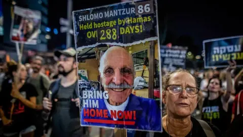 A woman holds up a placard with a picture of Shlomo Mantzur on it 