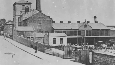 Lancashire Archives and Local History Black and white archive image of Massey's Bridge End Brewery on Westgate. It is a large imposing stone building with many attached smaller buildings and a long extension goes off to the right