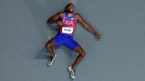 Noah Lyles lies on the track at the Stade de France