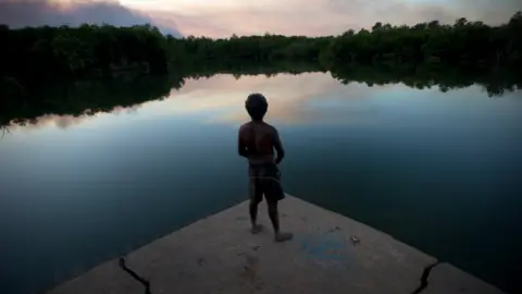 Getty Images Man stands looking out to lake