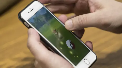 Getty Images Man playing Pokemon on phone