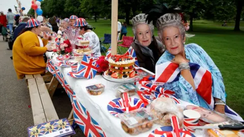 Reuters People dressed in union flag outfits and masks of the Queen at a Jubilee lunch in Windsor