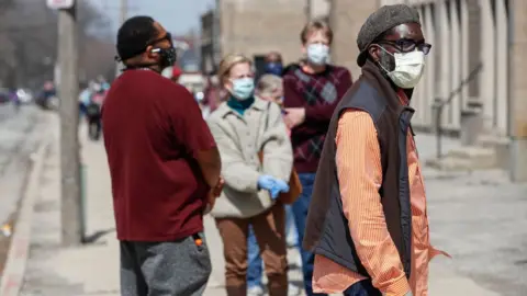 Getty Images Residents wait in long line to vote in a presidential primary election outside the Riverside High School in Milwaukee, Wisconsin, on 7 April, 2020