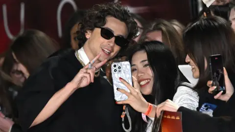 Getty Images Chalamet takes a selfie with an Asian fan