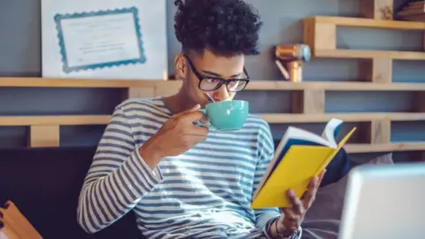 Getty Images Student reads and drinks cup of tea