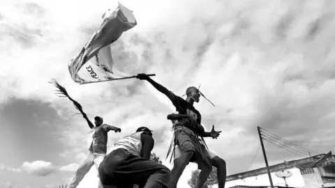 Glenn Edwards A Sierra Leonean flies a peace flag while standing on a truck