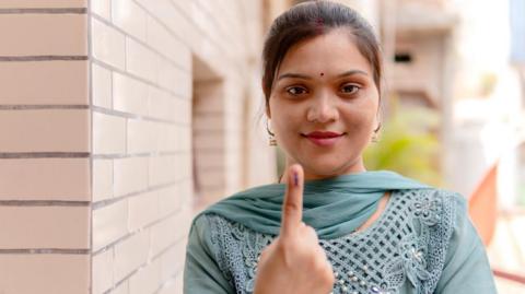 A woman with a marked finger to show she has voted