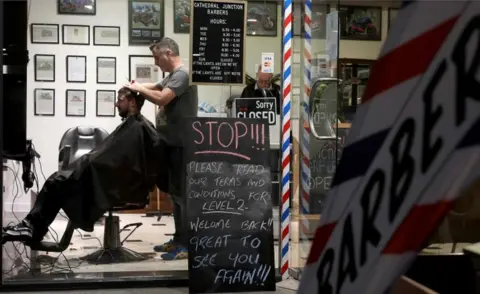 AFP/Getty Images A barber cuts a customer's hair in Christchurch, on 14 May, 2020.