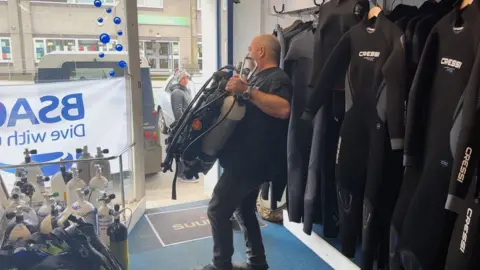 Seaways worker carries heavy oxygen cylinder