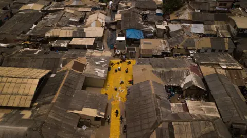 Nii Odzenma Aerial shot of yellow tapestry created by artist Serge Attukwei Clottey on roads in La - Accra, Ghana