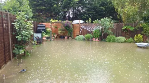 Rachael Blakey Wooden fenced garden under floodwater with washing line and plants around its edge