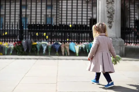 Reuters A little girl lays a bouquet of flowers outside Buckingham Palace