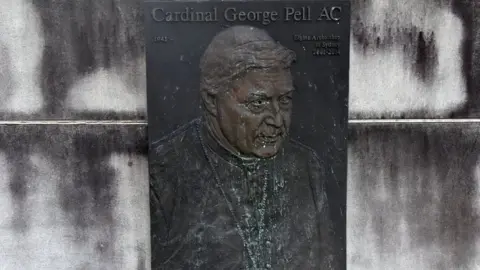 Reuters A faded plaque depicts George Pell below the words: "Cardinal George Pell AC"