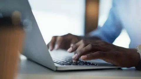 Hands typing on a laptop