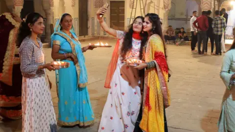 Getty Images Girls take selfie after light earthen lamps' diyas' on the occasion of Diwali festival at historical Ramchandra Ji temple , in Jaipur , Rajasthan , India ,on Thursday, Nov 04,2021.