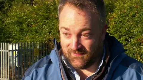 A man standing in front of a school fence