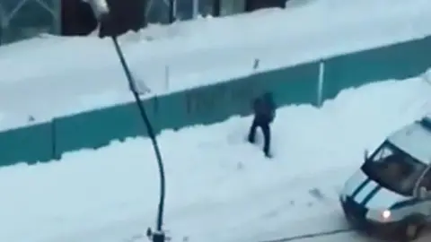Tatiana Sergeevna/YouTube Still from YouTube video of a man allegedly painting the word 'Putin' on a fence
