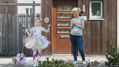 Getty Images Mother and daughter clapping outside their house