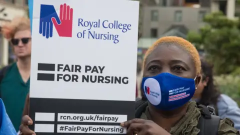 Getty Images A NHS nurse prepares to march from St Thomas' Hospital to Downing Street to protest against the NHS Pay Review Body's recommendation of a 3% pay rise for NHS staff in England on 30th July 2021 in London