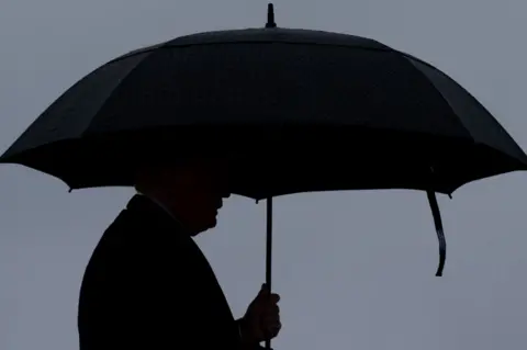 Getty Images Trump under an umbrella