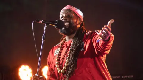 Inglefest Singer Da Fuchaman in a red top singing into a microphone