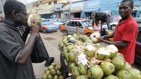 Getty Images A man drinks a coconut water by the roadside on the eve of presidential elections, in Accra on December 6, 2008
